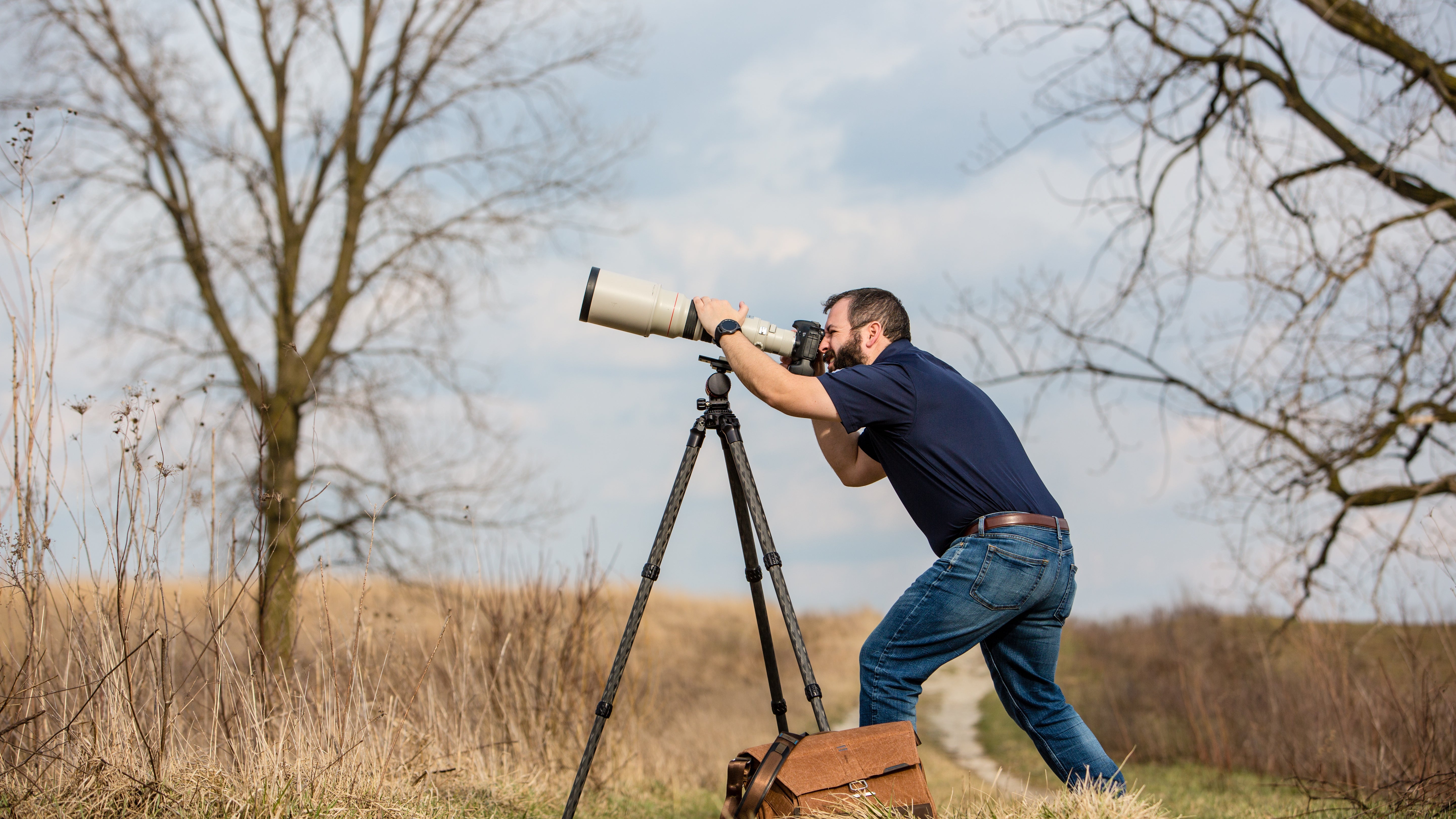 Man shooting with a telephoto lens using a ProMediaGear Carbon Fiber Tripod 